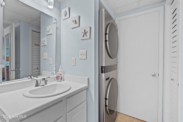 laundry room with light tile patterned flooring, stacked washing maching and dryer, and sink