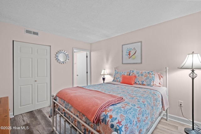 bedroom with hardwood / wood-style floors, a textured ceiling, and a closet