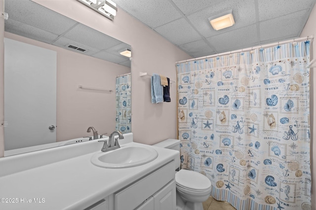 bathroom featuring a drop ceiling, toilet, walk in shower, and vanity