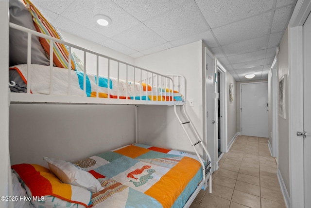 bedroom featuring tile patterned floors and a paneled ceiling