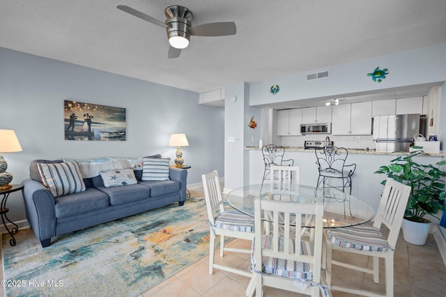 tiled dining space featuring a textured ceiling and ceiling fan