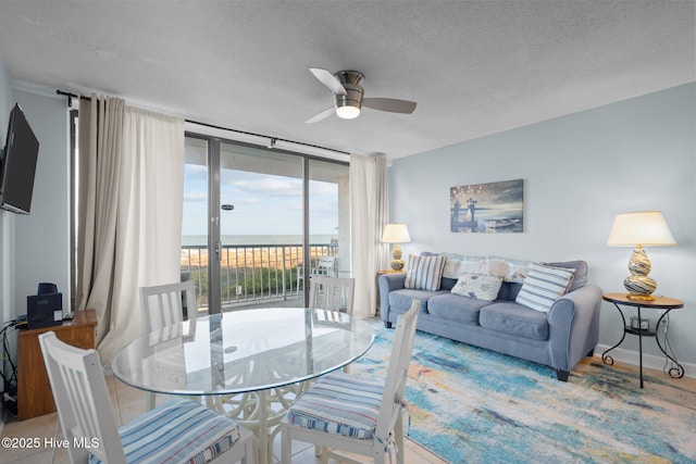 living room with ceiling fan, a textured ceiling, and a wall of windows