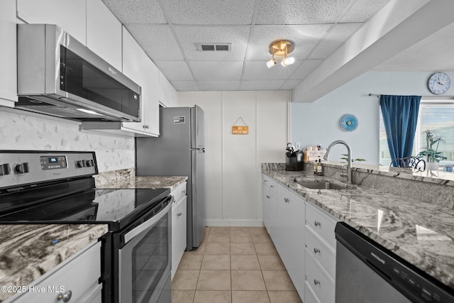 kitchen featuring a paneled ceiling, white cabinets, sink, light stone countertops, and stainless steel appliances