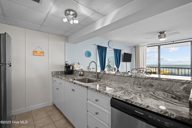 kitchen featuring white cabinetry, sink, ceiling fan, stainless steel appliances, and light stone counters