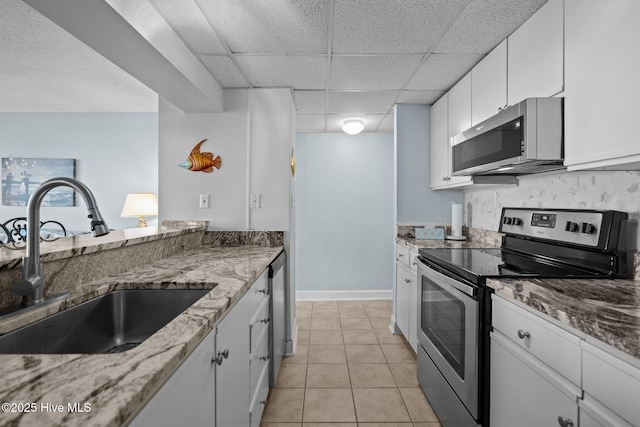 kitchen featuring a drop ceiling, white cabinets, sink, stone countertops, and stainless steel appliances