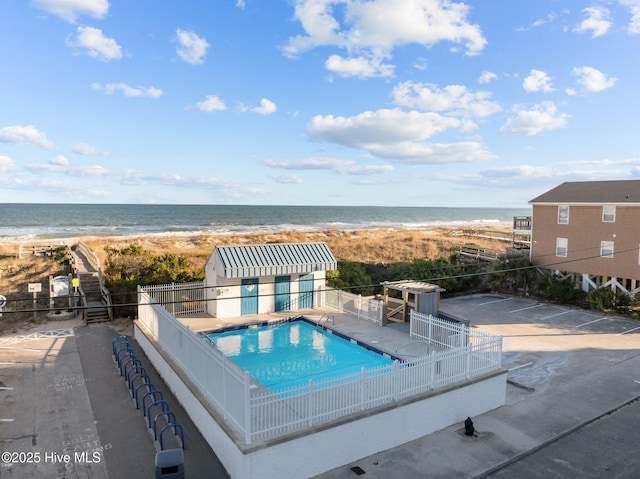 view of swimming pool with a beach view, a patio, and a water view