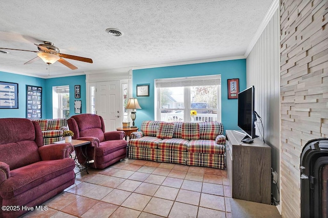 living room with ceiling fan, a textured ceiling, light tile patterned floors, and crown molding