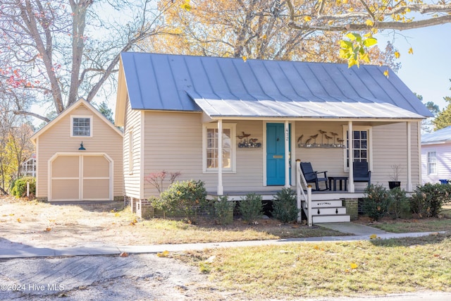 view of front facade featuring a porch, a garage, and an outbuilding