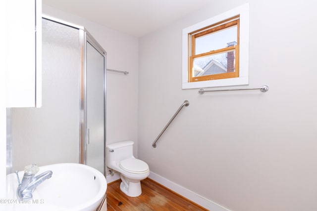 bathroom with hardwood / wood-style floors, toilet, a shower with door, and sink