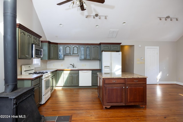 kitchen featuring sink, white appliances, dark wood-type flooring, and a wood stove