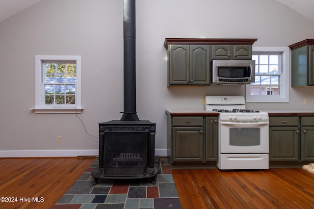 kitchen featuring dark hardwood / wood-style flooring, a wood stove, white range with gas cooktop, and plenty of natural light