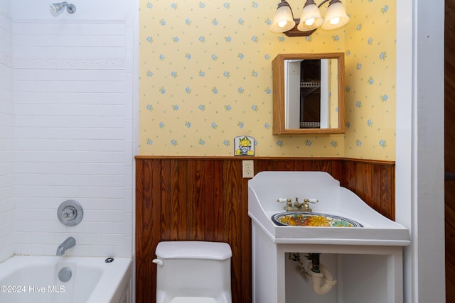 bathroom with wooden walls,  shower combination, and toilet