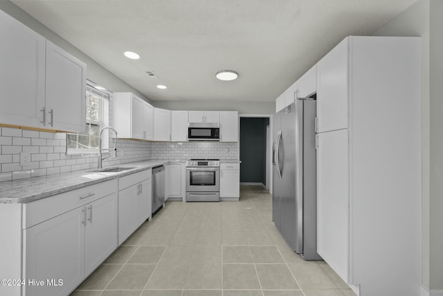 kitchen featuring white cabinets, light stone counters, sink, and stainless steel appliances