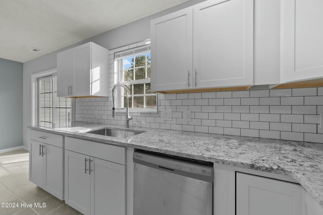 kitchen with backsplash, white cabinets, light stone counters, sink, and dishwasher