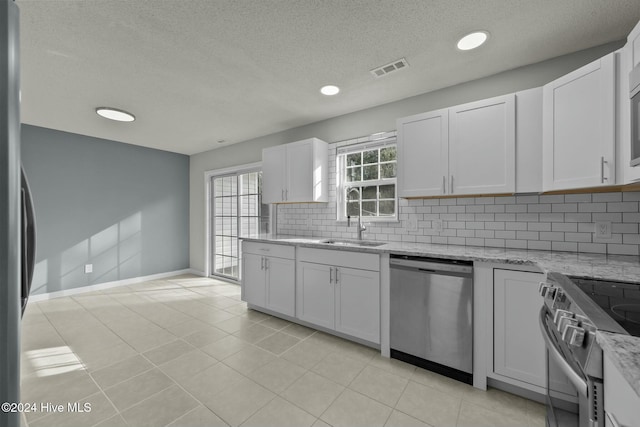 kitchen featuring light stone countertops, appliances with stainless steel finishes, white cabinetry, and sink