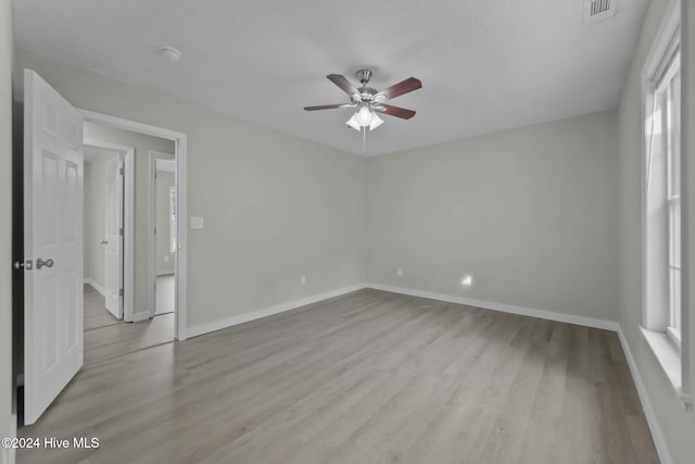 unfurnished room with a healthy amount of sunlight, ceiling fan, light hardwood / wood-style floors, and a textured ceiling