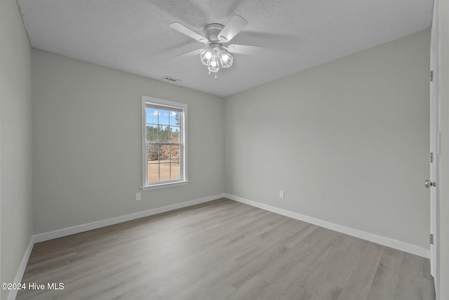 empty room with ceiling fan, a textured ceiling, and light wood-type flooring