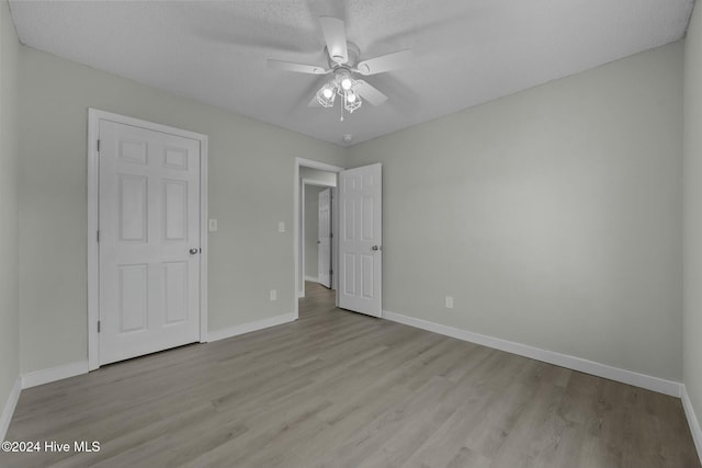 unfurnished bedroom featuring ceiling fan, light hardwood / wood-style floors, and a textured ceiling