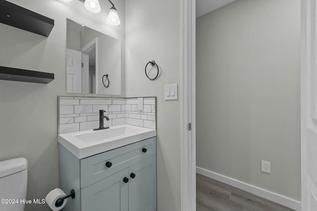 bathroom with decorative backsplash, wood-type flooring, vanity, and toilet