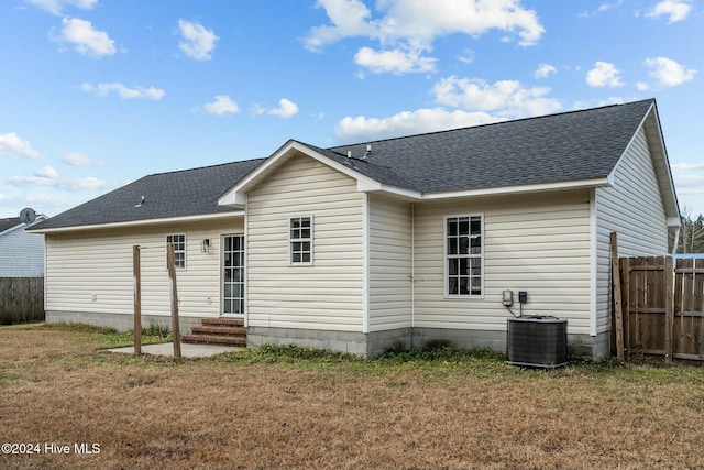 rear view of house featuring central air condition unit and a lawn