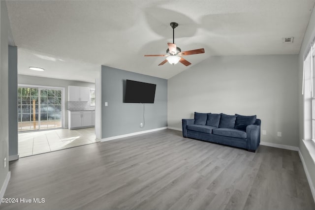 living room with ceiling fan, light hardwood / wood-style floors, and lofted ceiling