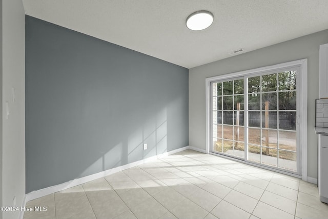 spare room featuring light tile patterned flooring and a textured ceiling