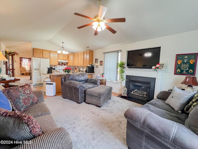 carpeted living room with ceiling fan with notable chandelier and vaulted ceiling