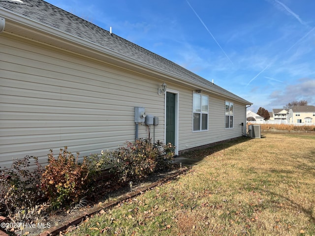 view of side of home featuring a lawn and cooling unit