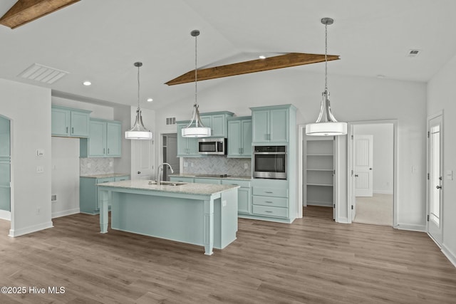 kitchen featuring pendant lighting, light wood-type flooring, stainless steel appliances, and a center island with sink