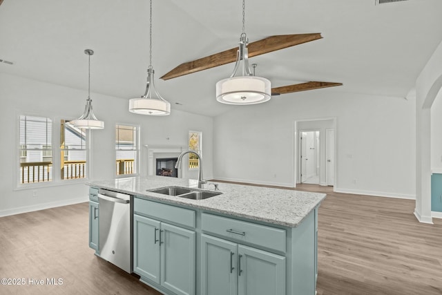 kitchen with sink, light stone counters, decorative light fixtures, a center island with sink, and stainless steel dishwasher