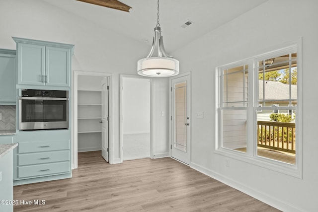 unfurnished dining area featuring vaulted ceiling and light wood-type flooring