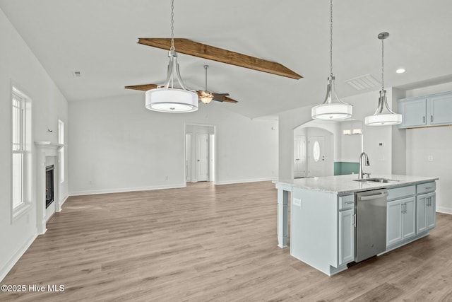 kitchen with sink, light stone counters, stainless steel dishwasher, an island with sink, and pendant lighting