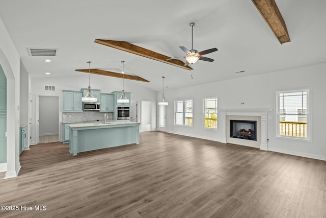 unfurnished living room featuring ceiling fan, sink, dark wood-type flooring, and beam ceiling