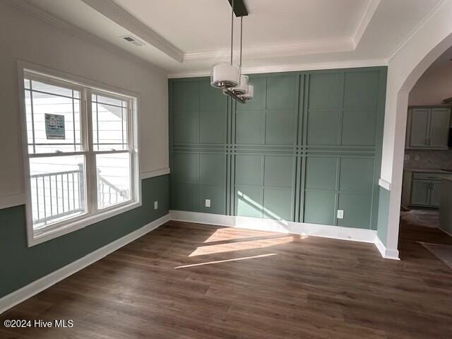 unfurnished dining area with a tray ceiling, crown molding, and dark wood-type flooring