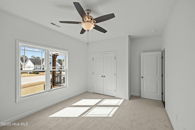 unfurnished bedroom featuring light colored carpet, a closet, and ceiling fan