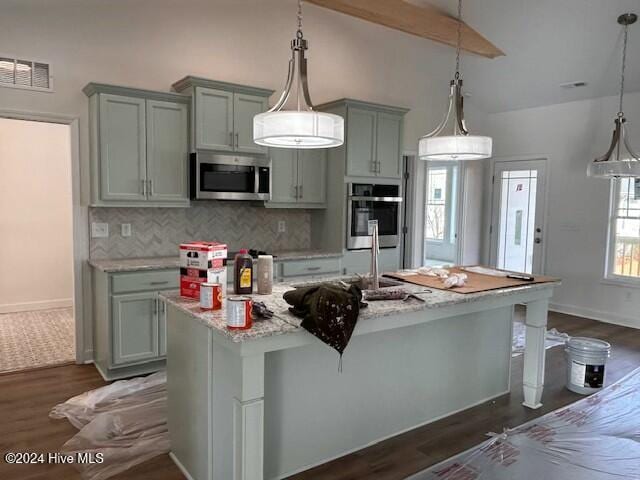 kitchen with pendant lighting, light stone countertops, a kitchen island with sink, and a breakfast bar area