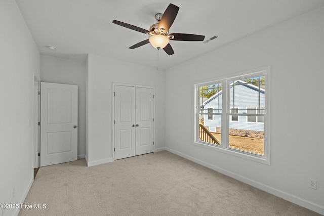 unfurnished bedroom with ceiling fan, light colored carpet, and a closet