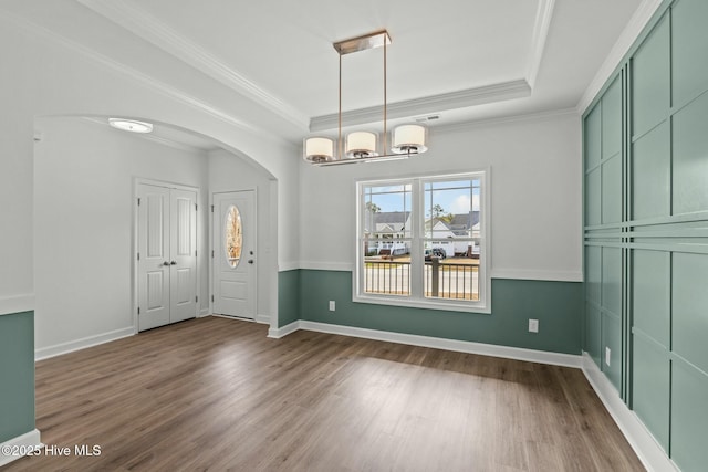 foyer entrance featuring crown molding, a tray ceiling, hardwood / wood-style floors, and a notable chandelier