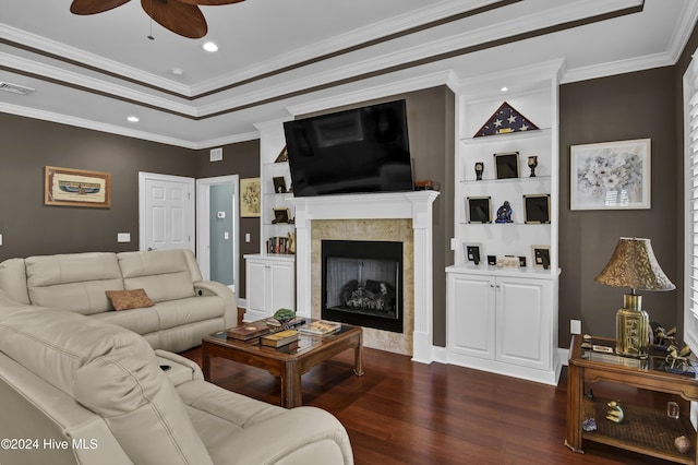 living room featuring dark hardwood / wood-style flooring, ceiling fan, crown molding, and a tiled fireplace