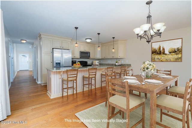 dining area with light hardwood / wood-style flooring and a notable chandelier