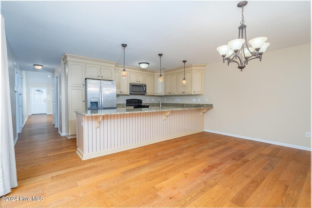 kitchen featuring an inviting chandelier, light stone counters, kitchen peninsula, appliances with stainless steel finishes, and light wood-type flooring