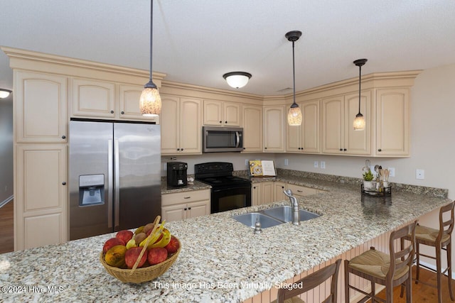 kitchen with light stone counters, sink, appliances with stainless steel finishes, and a breakfast bar area