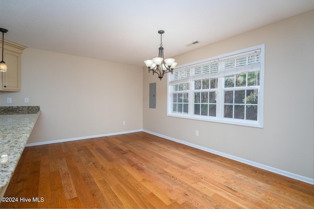 unfurnished dining area with electric panel, light hardwood / wood-style flooring, and a notable chandelier