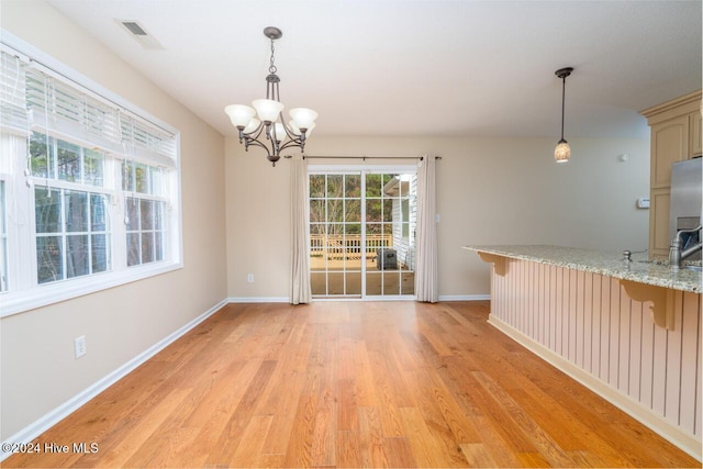 unfurnished dining area with a chandelier and light hardwood / wood-style floors