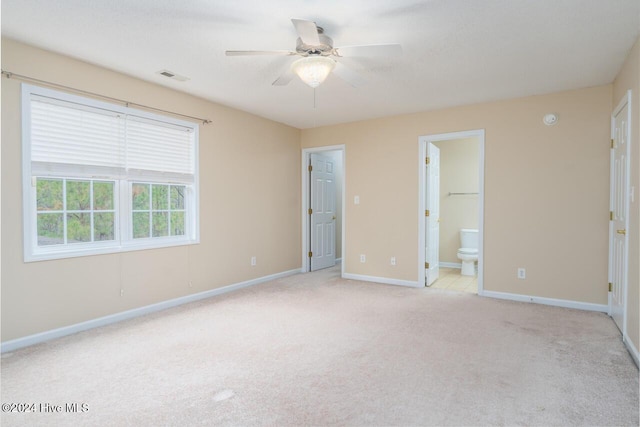 unfurnished bedroom with a walk in closet, ceiling fan, connected bathroom, light colored carpet, and a closet