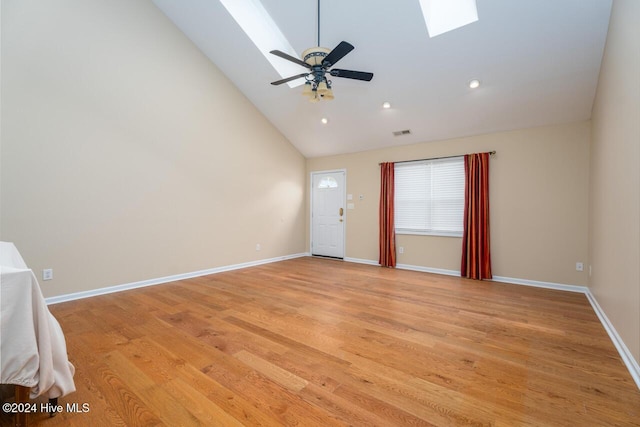 spare room with high vaulted ceiling, a skylight, light hardwood / wood-style flooring, and ceiling fan