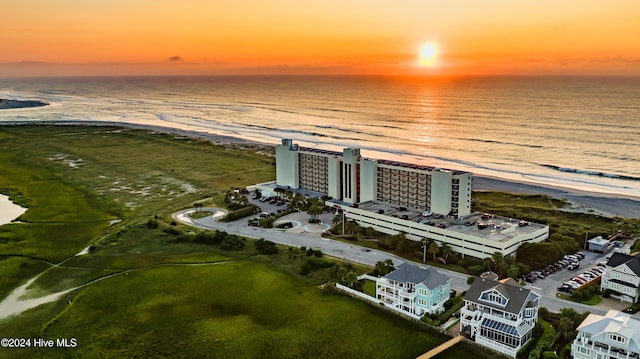 aerial view at dusk with a water view and a beach view