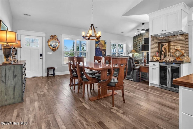 dining space with ceiling fan with notable chandelier, vaulted ceiling, hardwood / wood-style flooring, and wine cooler