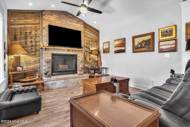 living room with hardwood / wood-style floors, ceiling fan, a brick fireplace, and lofted ceiling