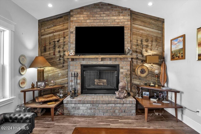 living room featuring lofted ceiling, a brick fireplace, and hardwood / wood-style floors